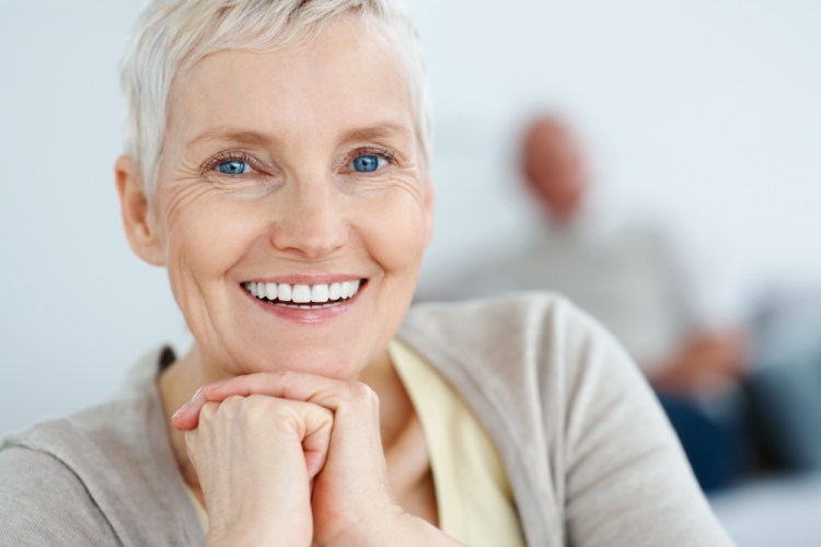 Closeup portrait of a happy elderly woman with hands together